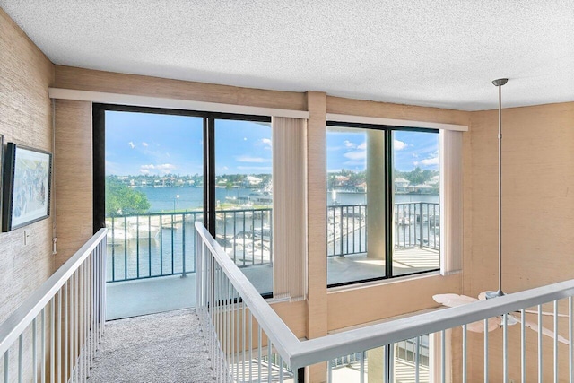 entryway featuring carpet, a water view, and a textured ceiling