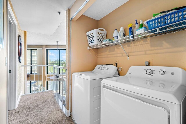 laundry room featuring carpet flooring, a textured ceiling, and washing machine and clothes dryer