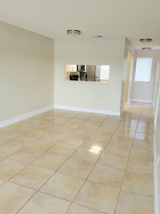 unfurnished living room with light tile patterned floors and a textured ceiling