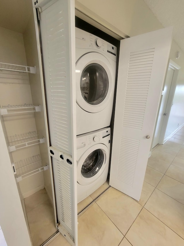 laundry area featuring light tile patterned floors and stacked washer / drying machine