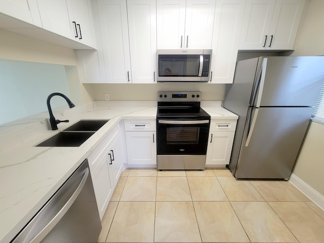 kitchen with light stone countertops, stainless steel appliances, sink, white cabinetry, and light tile patterned flooring