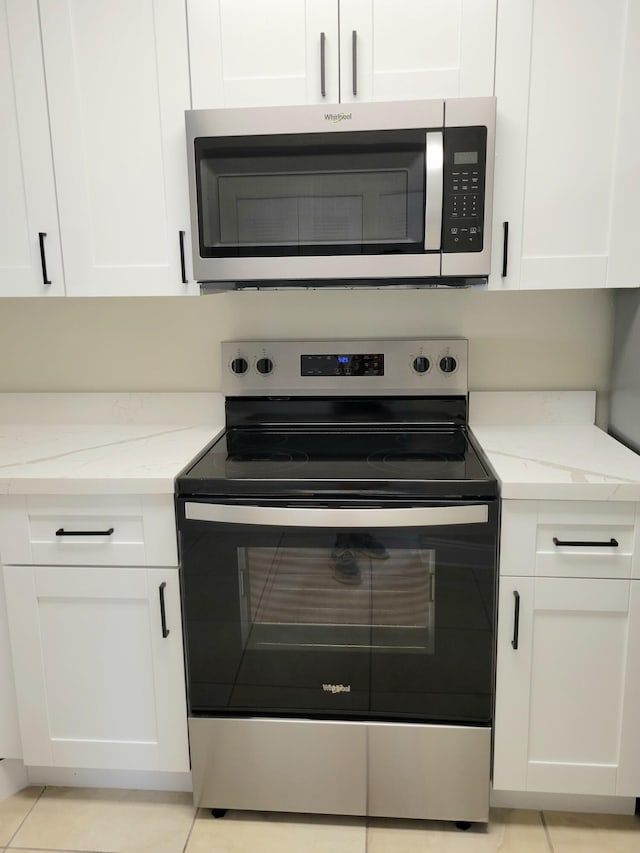 kitchen featuring light stone countertops, appliances with stainless steel finishes, and white cabinetry