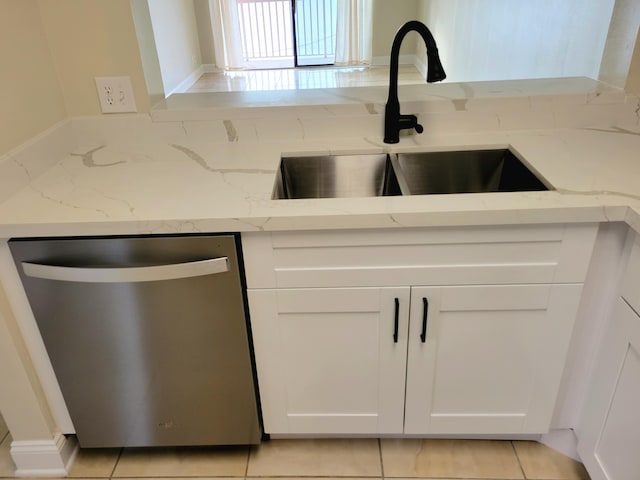 kitchen with stainless steel dishwasher, white cabinetry, light stone countertops, and sink