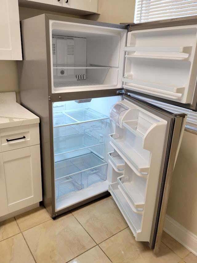 details featuring white cabinets, light tile patterned floors, and white refrigerator