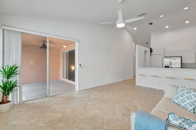 living room featuring ceiling fan, light tile patterned flooring, and lofted ceiling