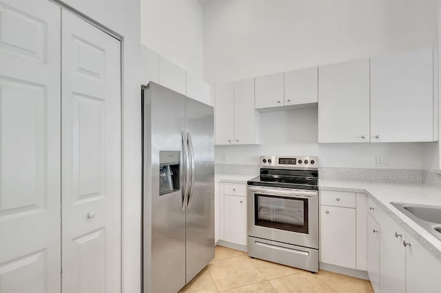 kitchen featuring light tile patterned floors, stainless steel appliances, white cabinetry, and sink