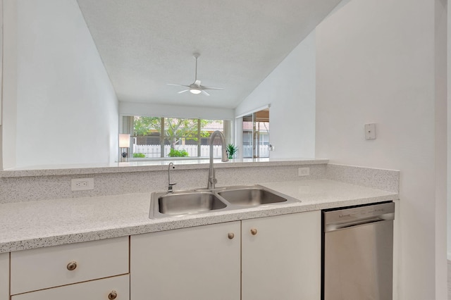 kitchen with light stone countertops, white cabinets, vaulted ceiling, sink, and dishwasher