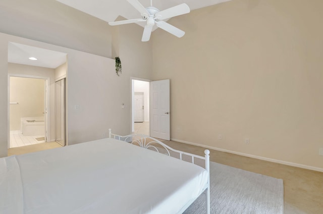 carpeted bedroom with a towering ceiling, connected bathroom, a closet, and ceiling fan