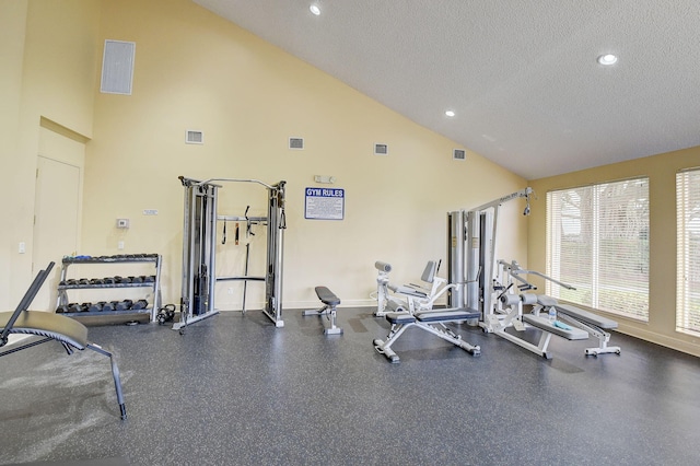 exercise room with high vaulted ceiling and a textured ceiling