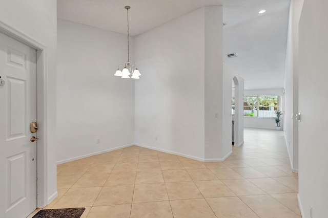 empty room featuring light tile patterned floors, high vaulted ceiling, and an inviting chandelier