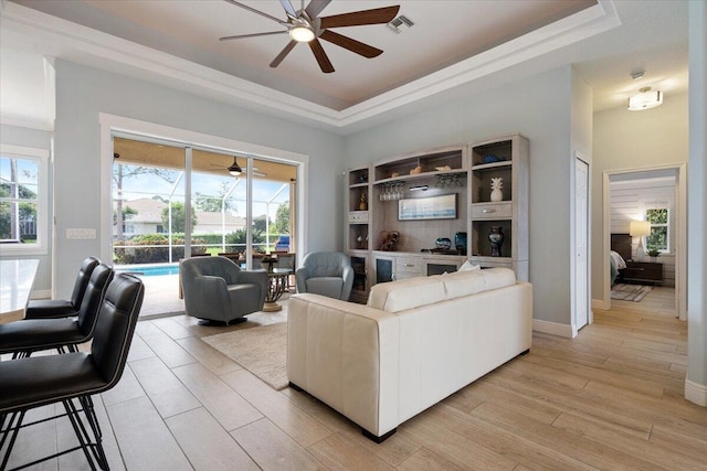 living room featuring light hardwood / wood-style floors, a raised ceiling, and ceiling fan