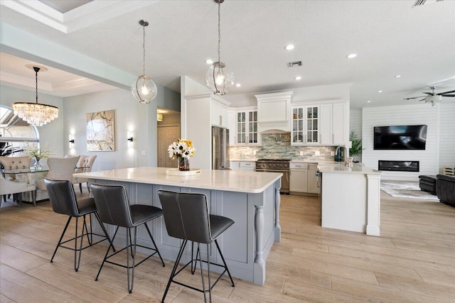 kitchen featuring pendant lighting, a breakfast bar area, light hardwood / wood-style flooring, white cabinetry, and stainless steel appliances