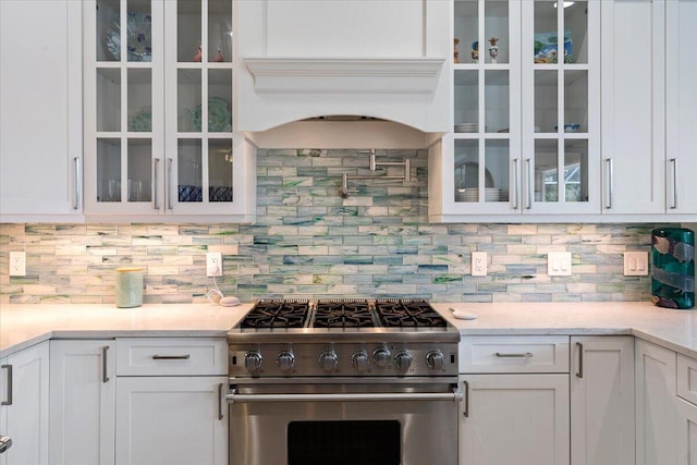 kitchen with high end range, tasteful backsplash, and white cabinetry