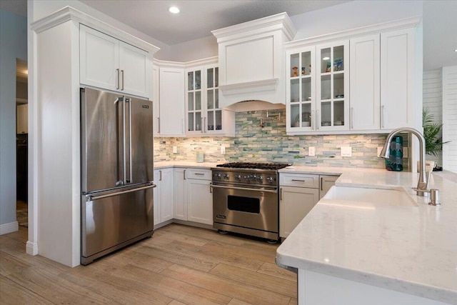 kitchen featuring light wood-type flooring, white cabinetry, high end appliances, and sink