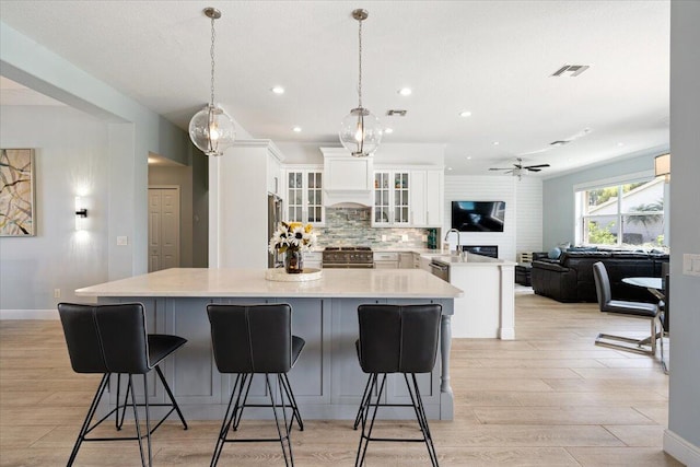 kitchen with a breakfast bar area, white cabinetry, stainless steel range, and hanging light fixtures