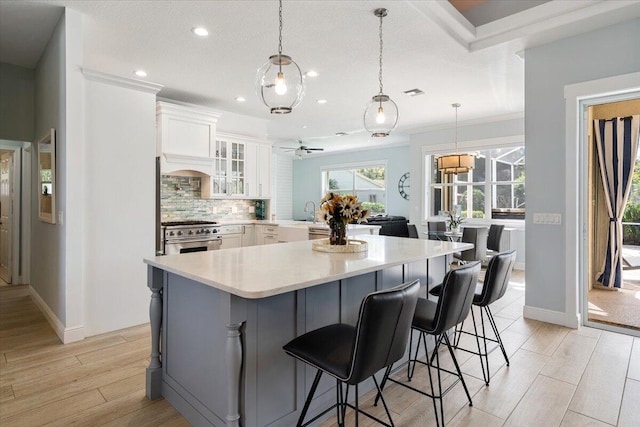 kitchen with decorative light fixtures, white cabinetry, a breakfast bar, and light hardwood / wood-style flooring