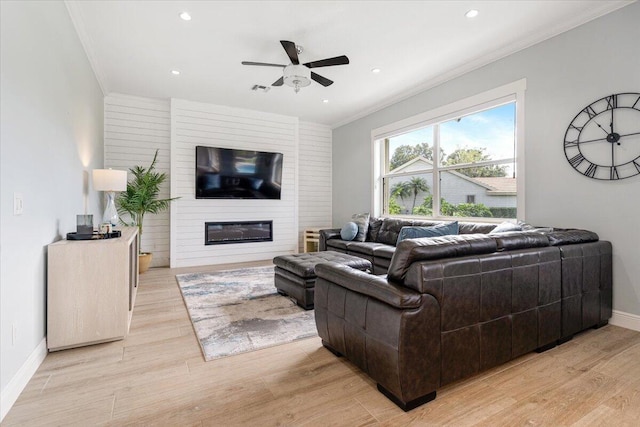 living room with a fireplace, light hardwood / wood-style flooring, ceiling fan, and crown molding