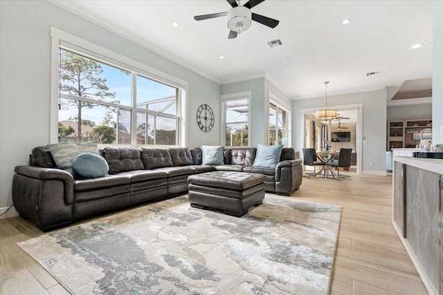 living room featuring light wood-type flooring, ornamental molding, and a wealth of natural light