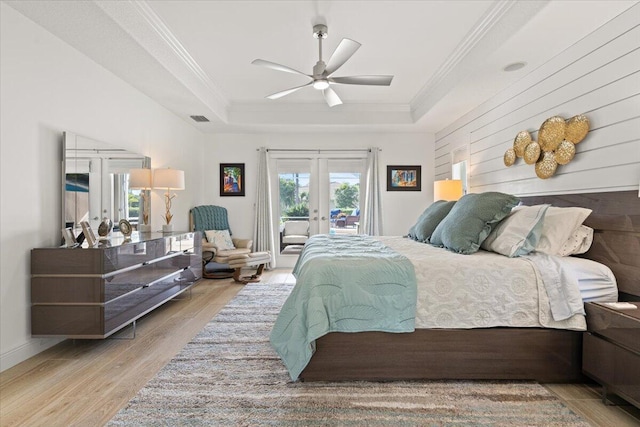 bedroom featuring ceiling fan, a raised ceiling, light wood-type flooring, and french doors