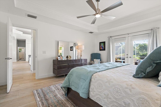 bedroom featuring crown molding, light hardwood / wood-style flooring, ceiling fan, access to exterior, and a tray ceiling