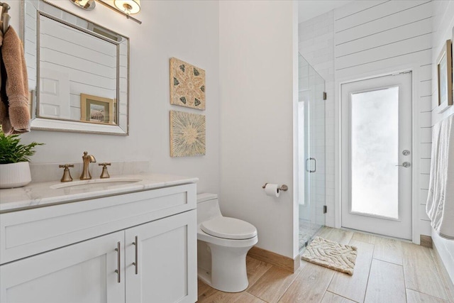 bathroom with toilet, vanity, a shower with shower door, and hardwood / wood-style flooring