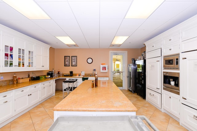 kitchen featuring light tile patterned floors, a center island, stainless steel appliances, and white cabinetry