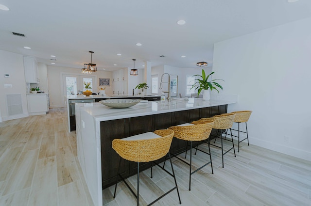 kitchen featuring kitchen peninsula, a breakfast bar, decorative light fixtures, and white cabinetry