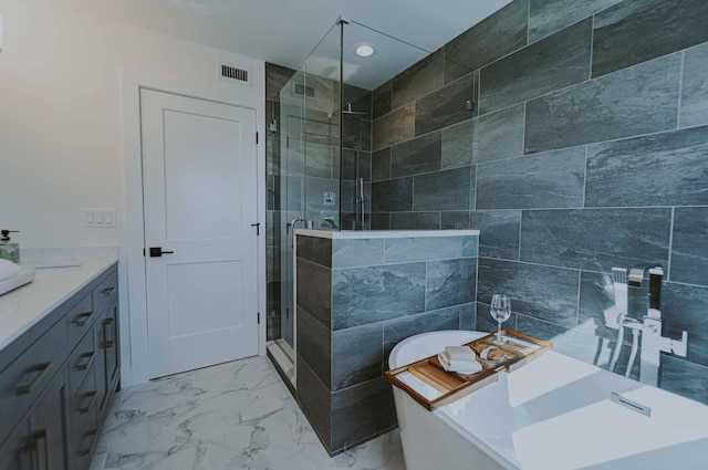 bathroom featuring plus walk in shower, vanity, and tile walls