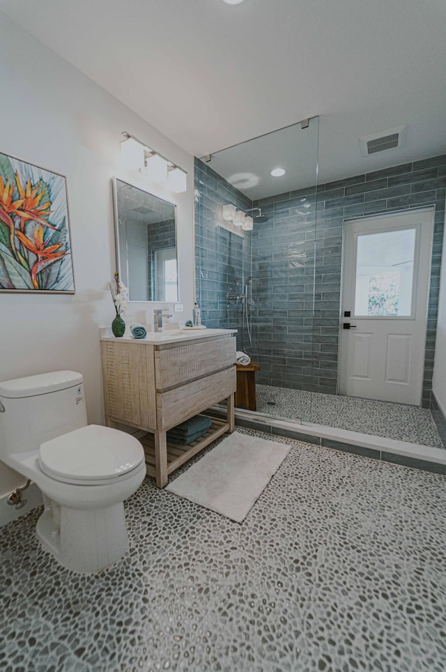 bathroom featuring tiled shower, vanity, toilet, and tile patterned flooring