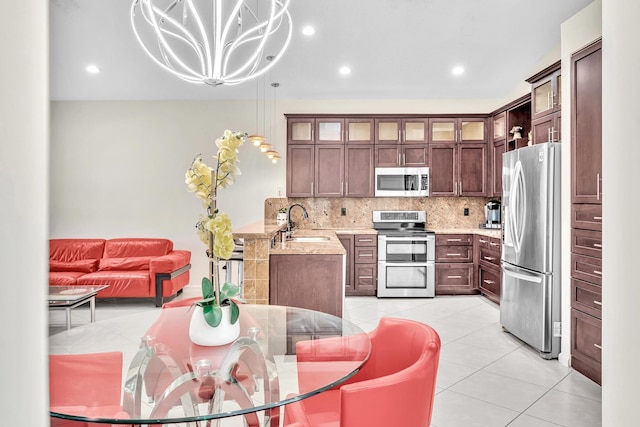 kitchen with light stone countertops, sink, hanging light fixtures, decorative backsplash, and appliances with stainless steel finishes