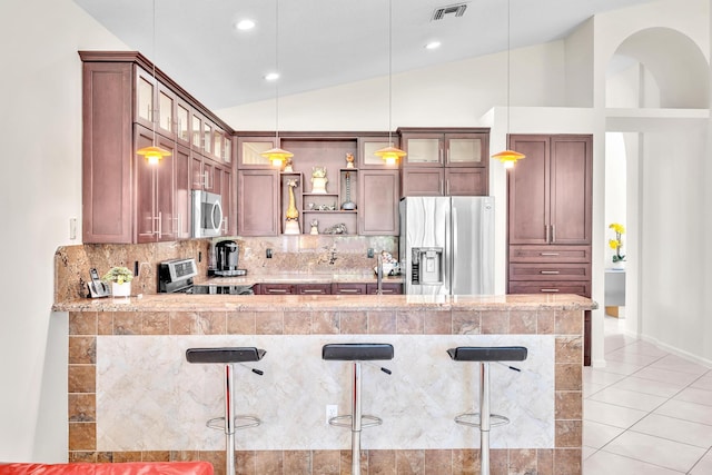 kitchen featuring a breakfast bar, appliances with stainless steel finishes, and vaulted ceiling