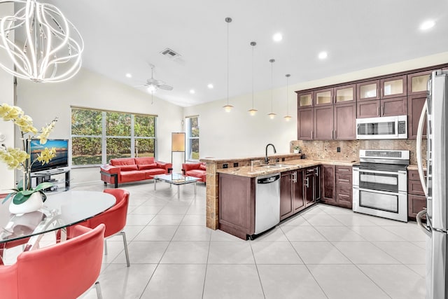 kitchen featuring decorative light fixtures, stainless steel appliances, ceiling fan with notable chandelier, and vaulted ceiling