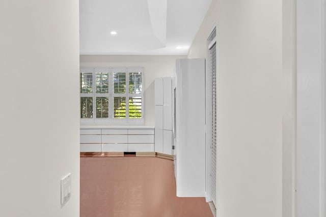 hallway with tile patterned floors and a tray ceiling