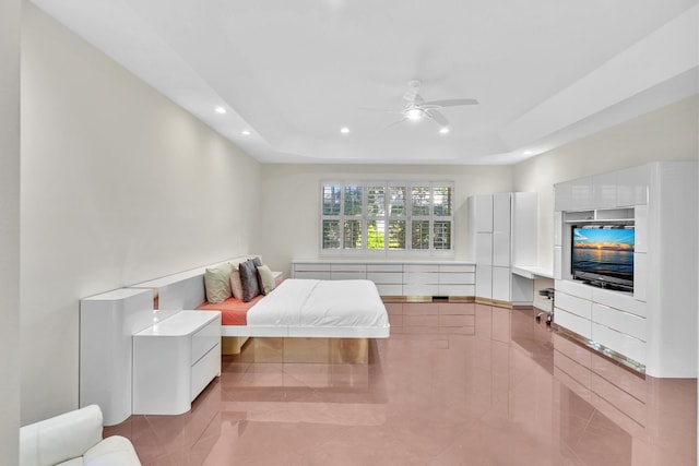 bedroom featuring ceiling fan, a raised ceiling, and light tile patterned floors