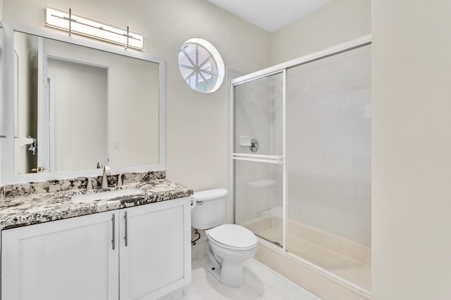 bathroom featuring tile patterned flooring, vanity, toilet, and a shower with door