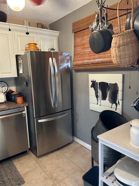 kitchen with white cabinets, light tile patterned flooring, a textured ceiling, and appliances with stainless steel finishes