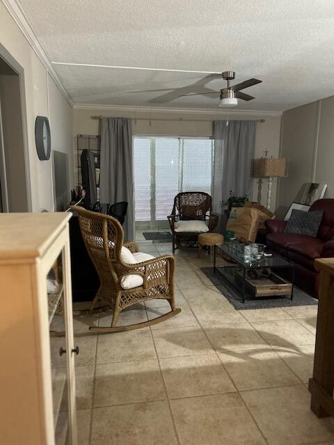 tiled living room featuring a textured ceiling, ceiling fan, and crown molding