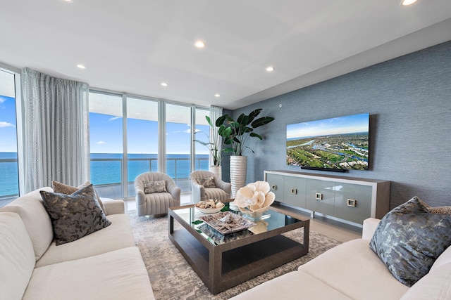 living room featuring light hardwood / wood-style floors, expansive windows, and a water view