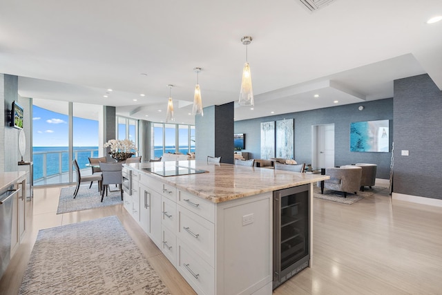 kitchen featuring wine cooler, light stone counters, hanging light fixtures, a kitchen island, and white cabinets