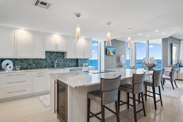 kitchen with white cabinetry, a water view, beverage cooler, and a kitchen island