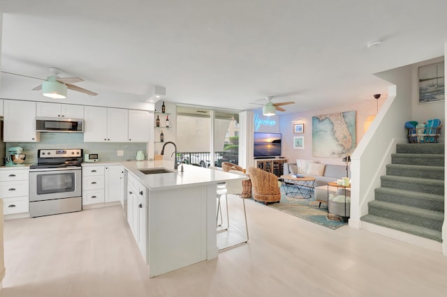 kitchen featuring decorative backsplash, appliances with stainless steel finishes, ceiling fan, sink, and white cabinets