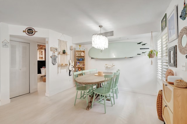 dining room with light hardwood / wood-style flooring and a notable chandelier