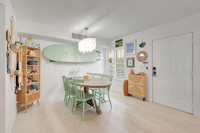 dining area with a notable chandelier and light hardwood / wood-style floors