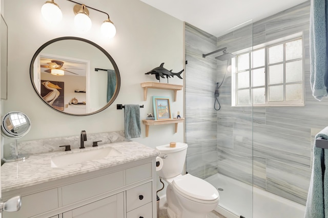 bathroom with a tile shower, vanity, toilet, and ceiling fan