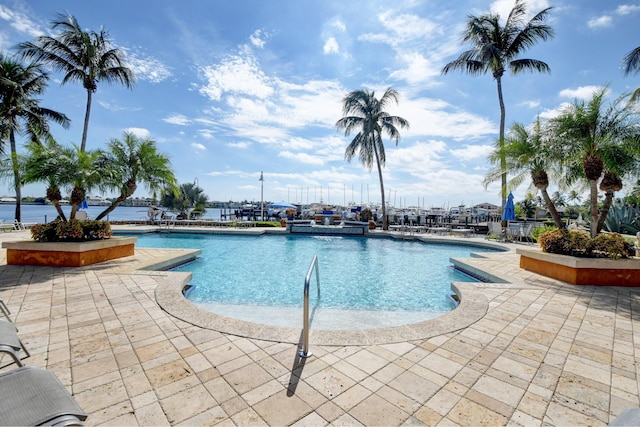 view of swimming pool with a patio area and a water view