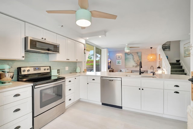 kitchen with kitchen peninsula, stainless steel appliances, white cabinetry, and sink