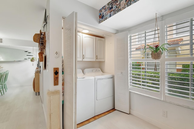 clothes washing area featuring cabinets, independent washer and dryer, and light hardwood / wood-style flooring