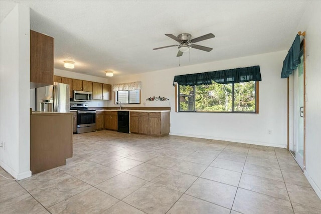 kitchen with sink, ceiling fan, light tile patterned floors, a textured ceiling, and appliances with stainless steel finishes