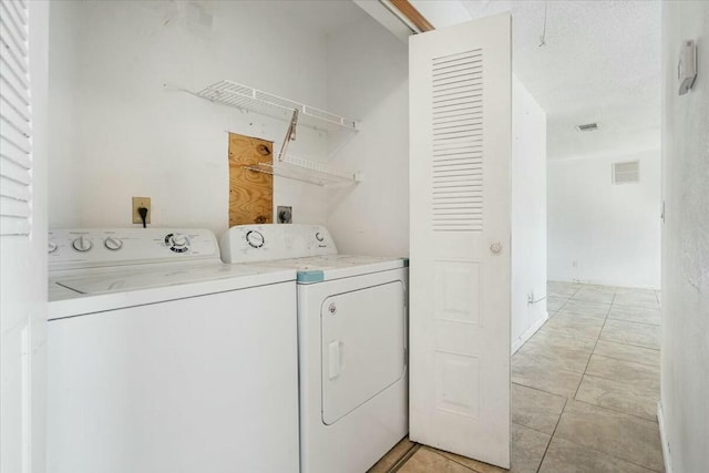 laundry room with light tile patterned floors, a textured ceiling, and washing machine and clothes dryer