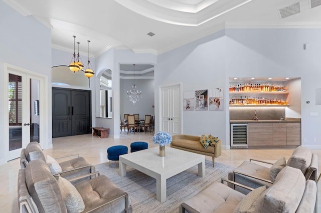 living room with wine cooler, a towering ceiling, crown molding, and a notable chandelier